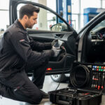 À quoi sert le diagnostic Gutmann dans un atelier automobile Technicien automobile utilisant une valise de diagnostic professionnelle pour contrôler une voiture récente dans un atelier moderne.