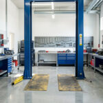Les 8 équipements indispensables pour moderniser un atelier automobile Atelier automobile moderne et lumineux avec un pont élévateur, des outils rangés sur les murs et des établis propres et bien organisés.
