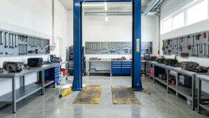 Atelier automobile moderne et lumineux avec un pont élévateur, des outils rangés sur les murs et des établis propres et bien organisés.